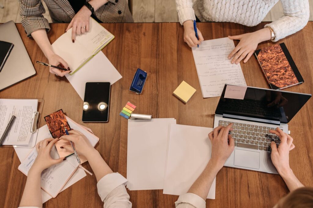 Top view of a team planning and working together in an office setting with laptops and notepads.